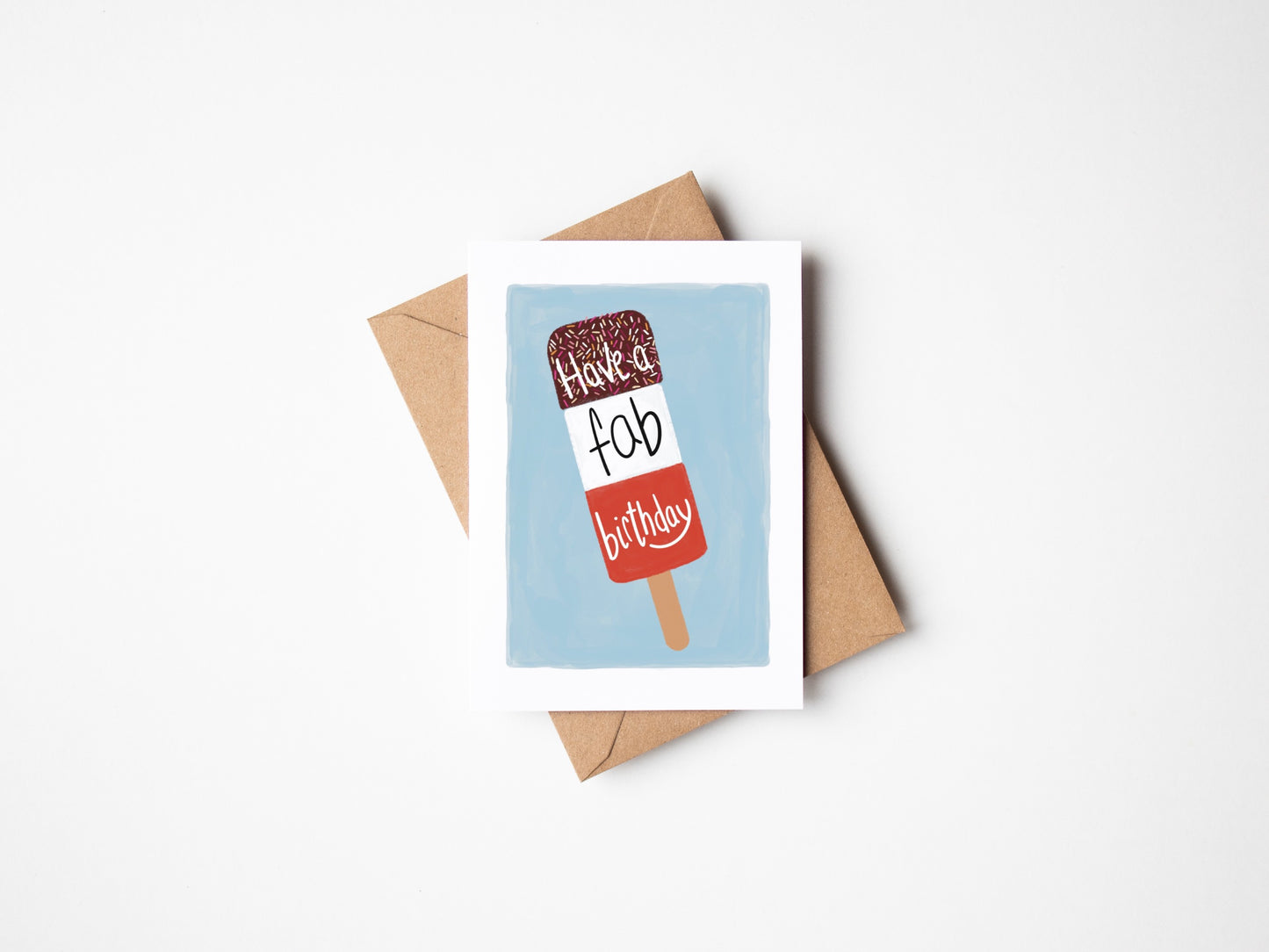A6 premium textured recyclable greeting card with white border, blue background and a FAB ice lolly with the words “ have a fab birthday” in handwritten text. Brown Kraft envelope included.