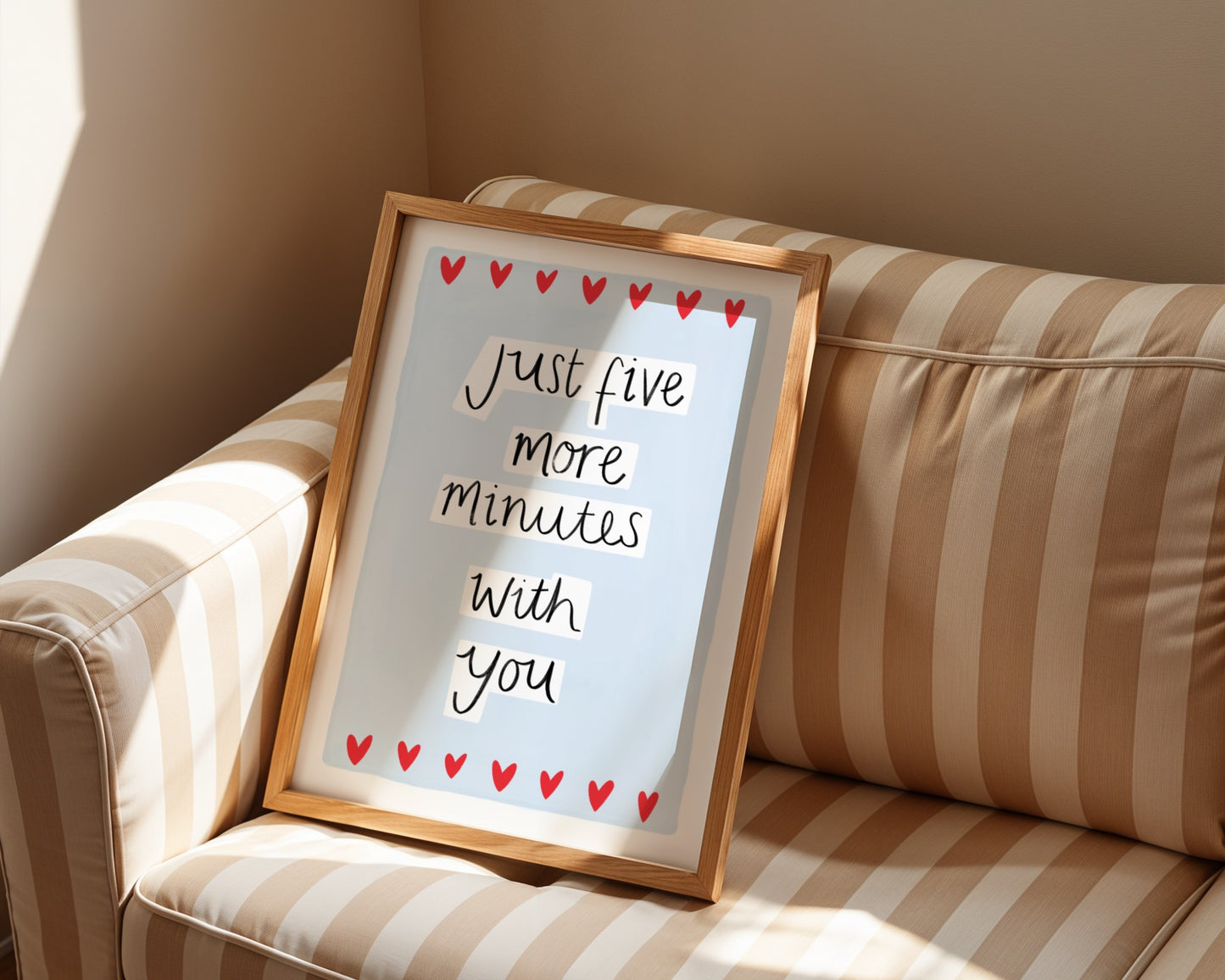 Framed sign with 'Just five more minutes with you' on a striped couch