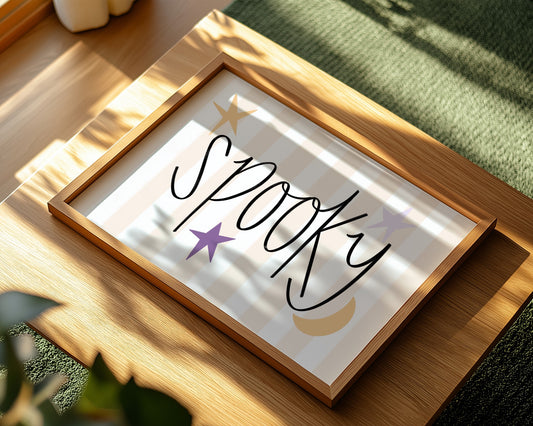 Framed artwork with 'Spooky' text on a wooden surface