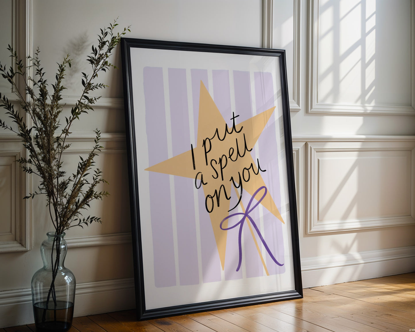 Framed artwork with a yellow star and text on a striped background, placed on a wooden floor.