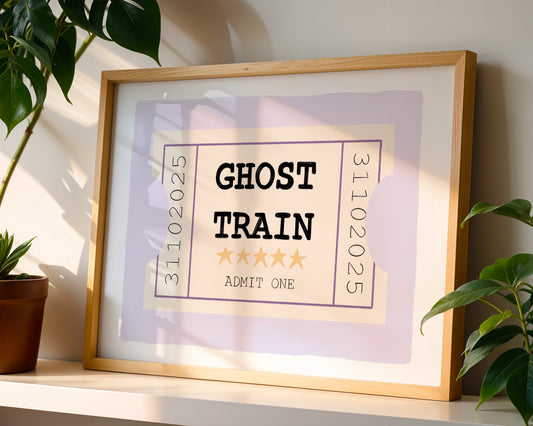 Framed poster with 'Ghost Train' design on a shelf with plants