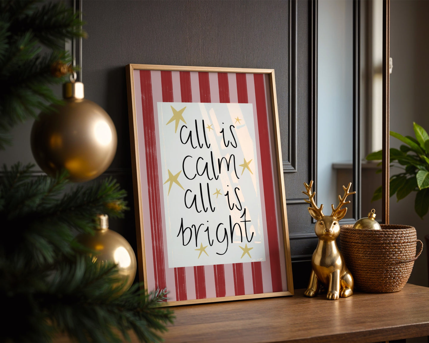 Framed Christmas art print with 'all is calm, all is bright' text on a decorative shelf.