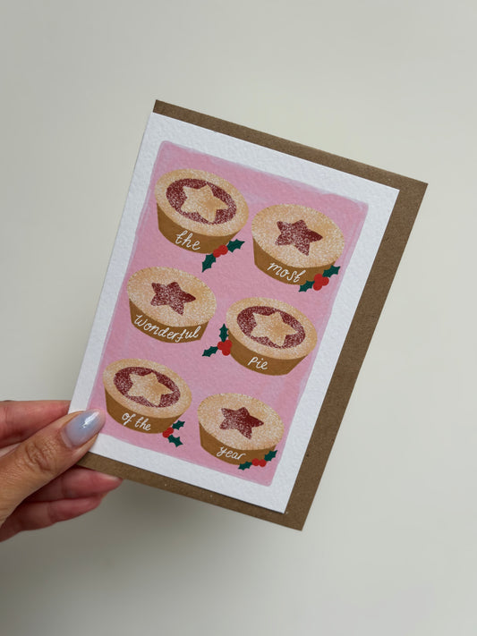 Card with illustrations of pies on a pink background held by a hand.