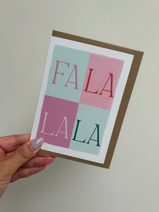 Card with 'FALA LA LA' text held by a hand against a plain background