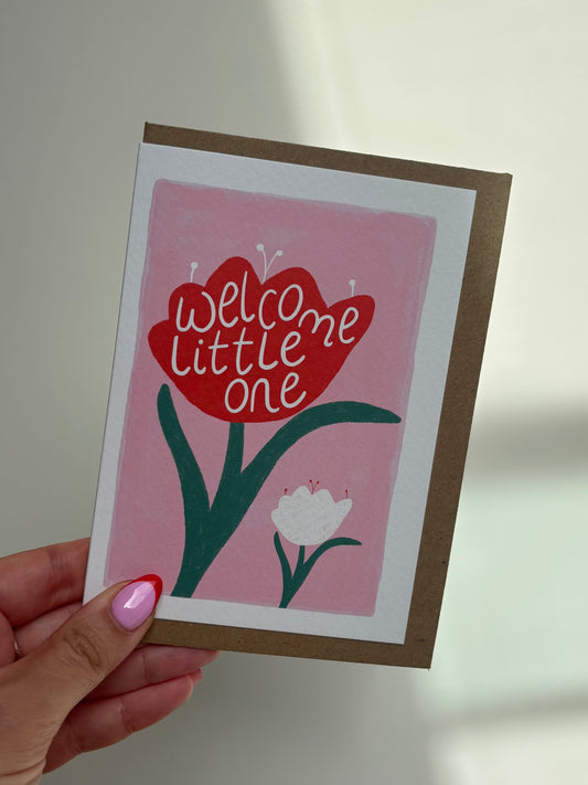 A6 premium textured recyclable card with pink background, and illustration of one large red tulip with the words “welcome little one” sat next to a smaller white tulip. Brown Kraft envelope included.