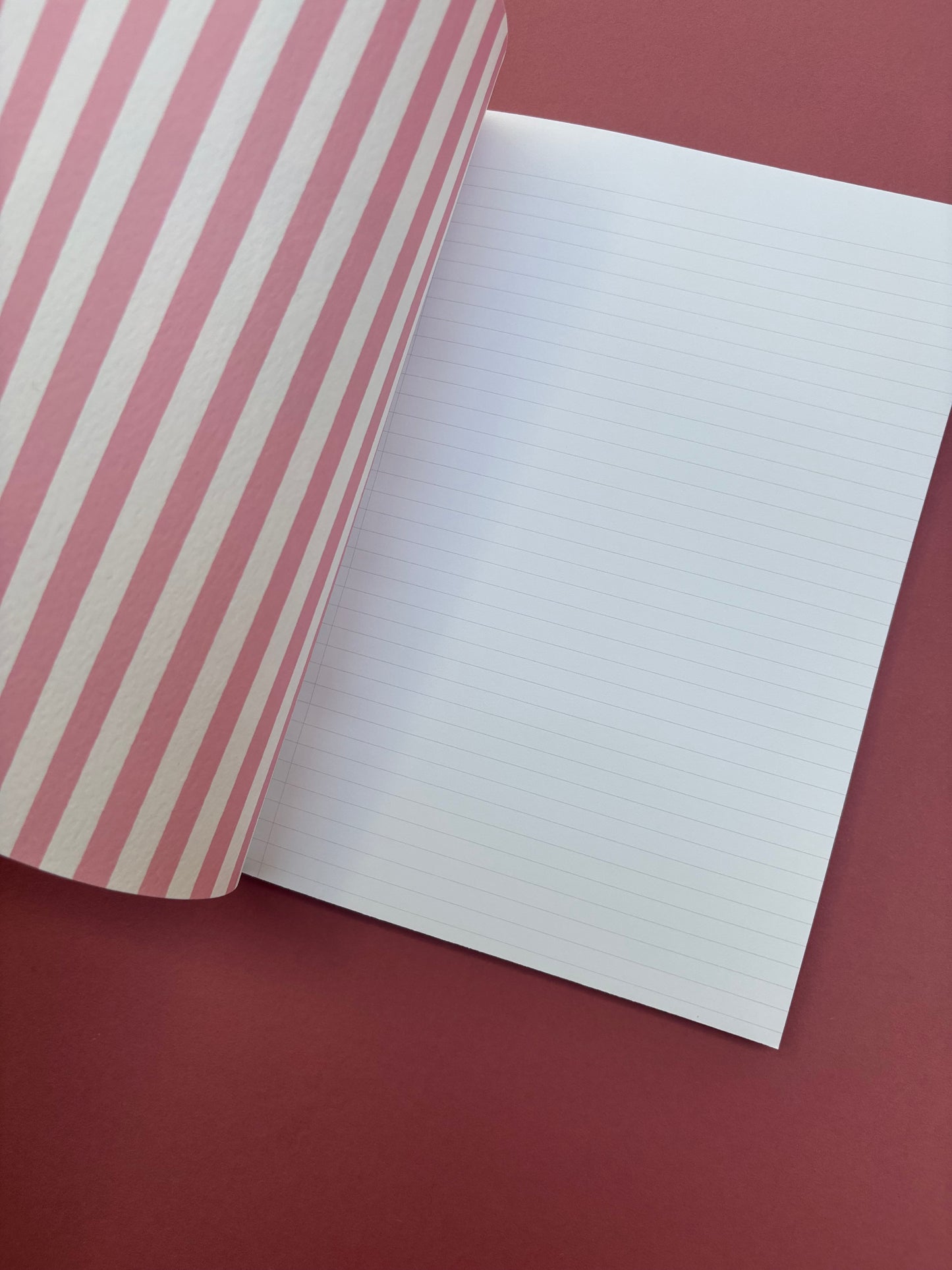 A5 lined notebook with pink and white stripes and large strawberry detail with green binding and word “notes”