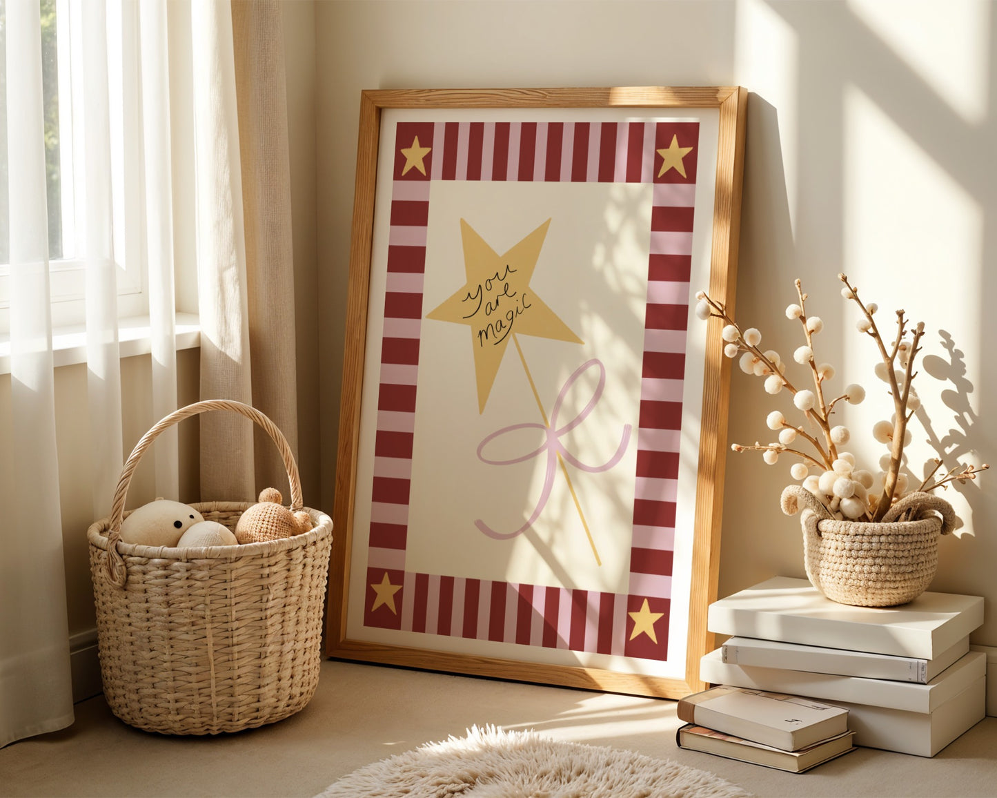 Kids wall art with pink and burgundy striped border and yellow stars in the corners and a central illustration of yellow star wand tied with a pink bow and words “you are magic”