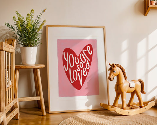 Kids wall art with pink background a red heart illustration featuring “you are so loved” quote