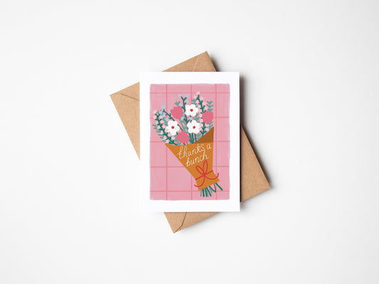 A6 recyclable greeting card with white border, pink grid background and a bunch of pastel flowers wrapped in brown paper tied with a red bow. Brown Kraft envelope included.
