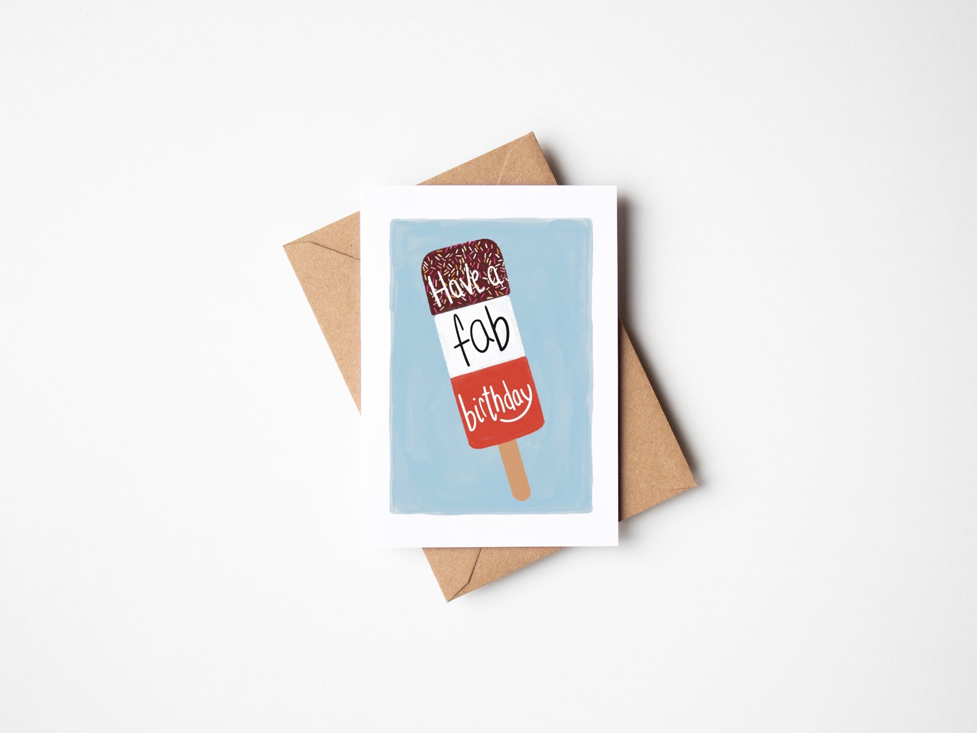 A6 premium textured recyclable greeting card with white border, blue background and a FAB ice lolly with the words “ have a fab birthday” in handwritten text. Brown Kraft envelope included. 