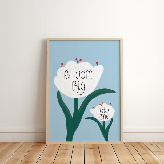 Framed artwork with a flower illustration and text on a light blue background, leaning against a white wall.