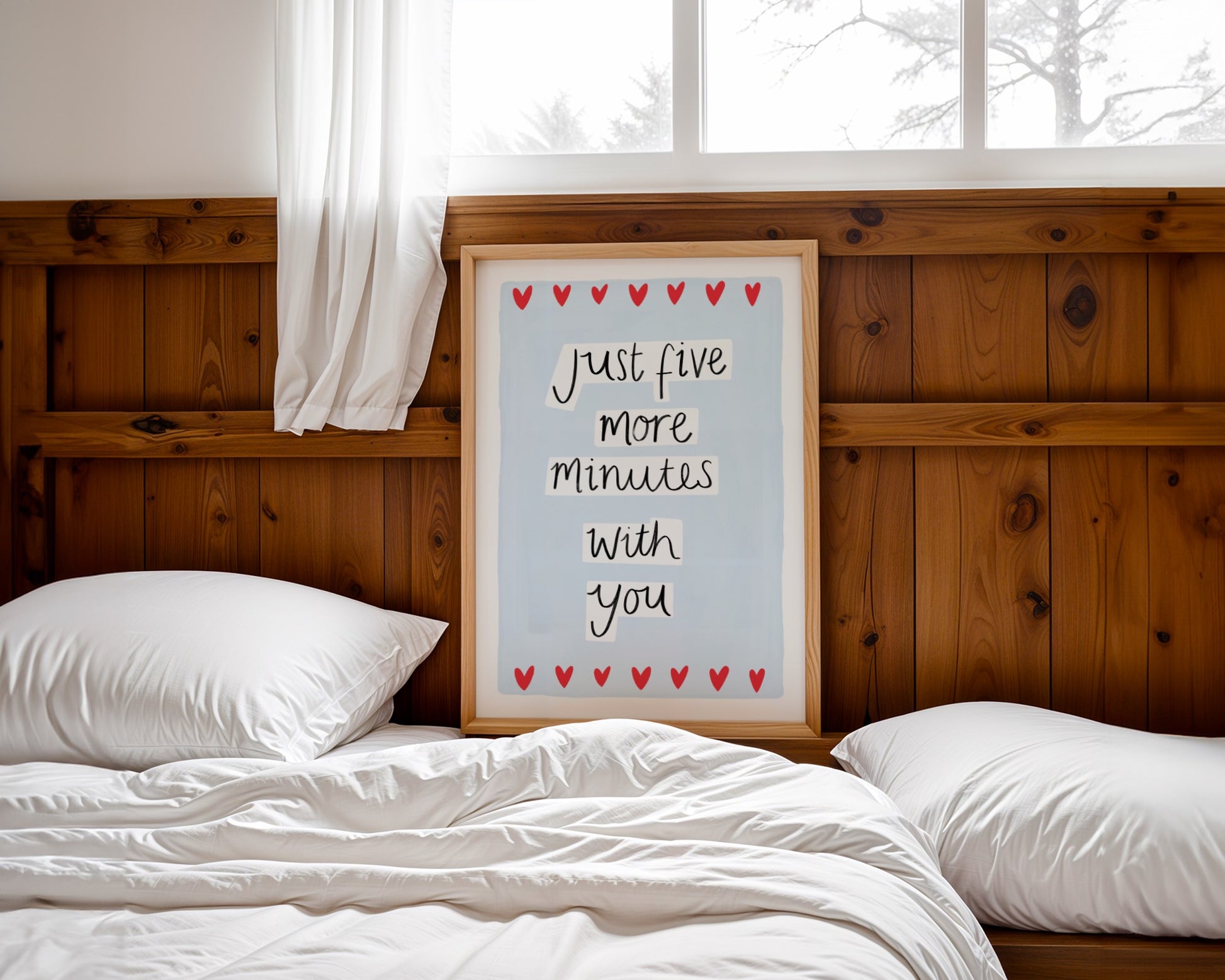 Bedroom with wooden headboard, white pillows, and a framed sign reading 'Just five more minutes with you' on a snowy day.