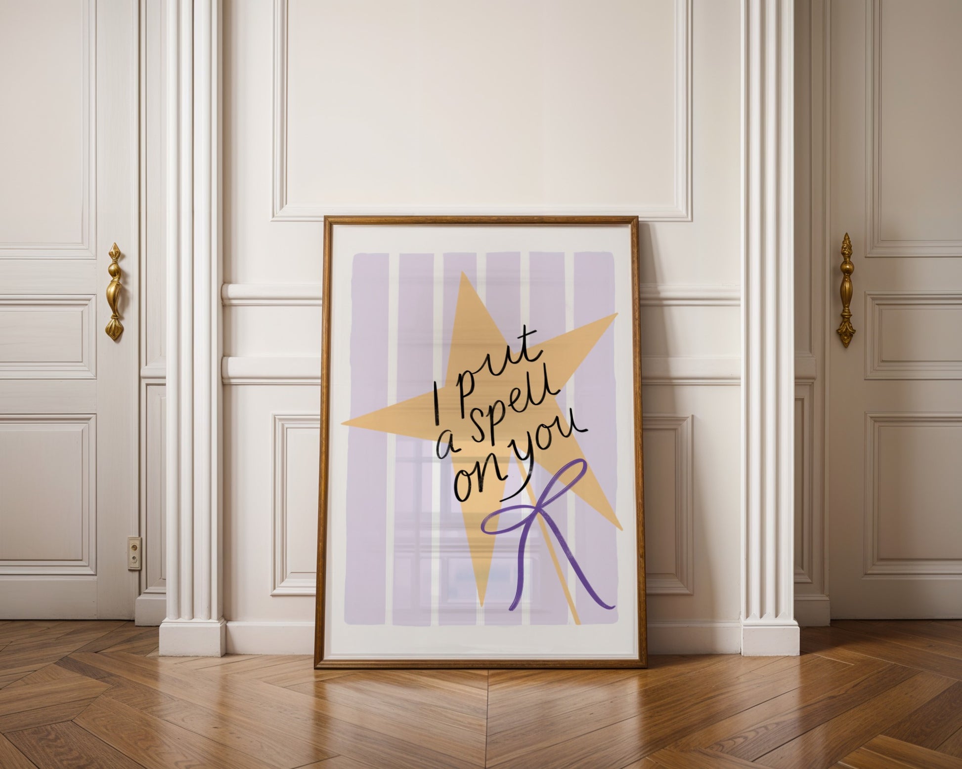 Framed artwork with a star design and text on a wall in a room with wooden flooring.
