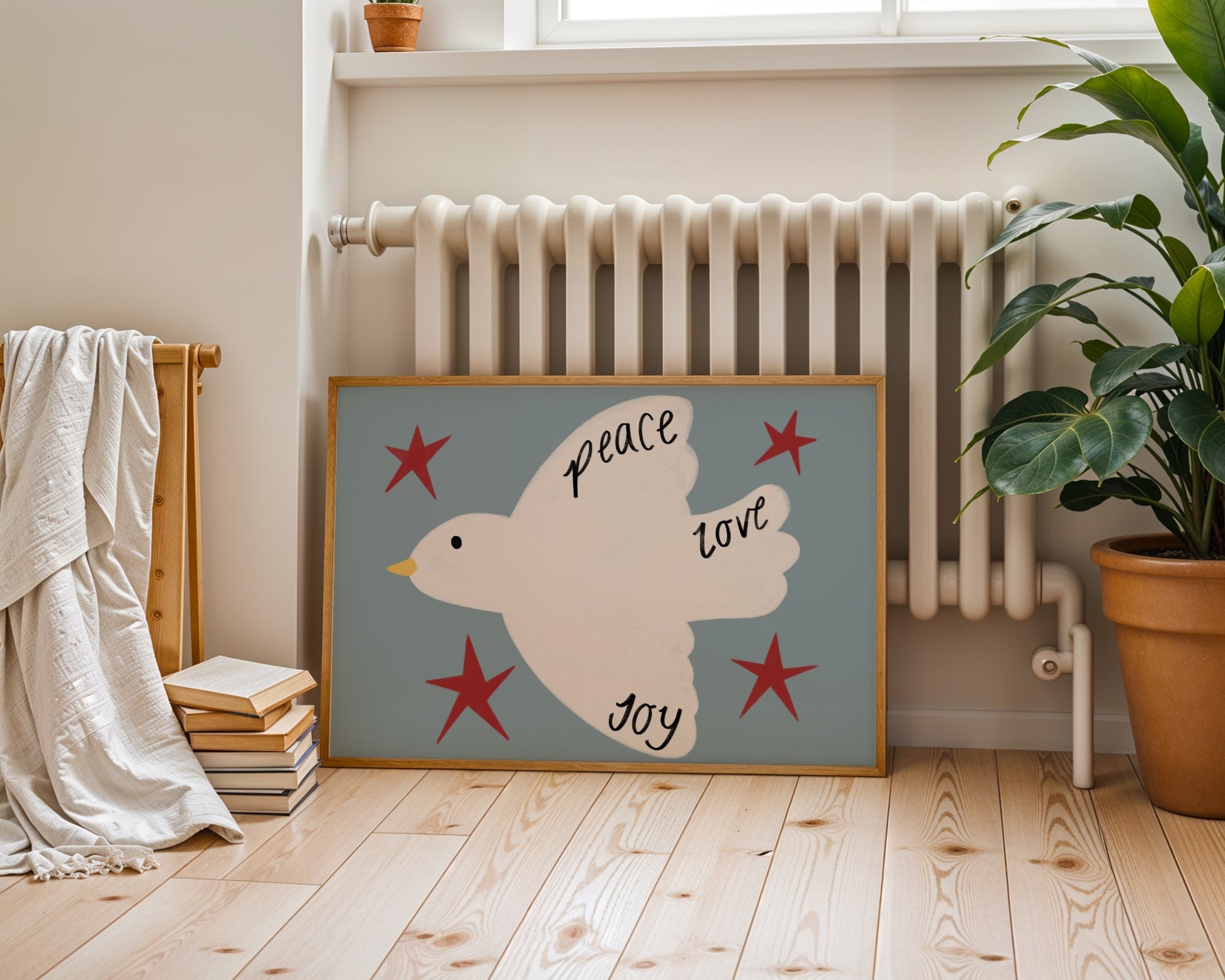 Framed artwork of a dove with stars and text in a room with a radiator and plant.