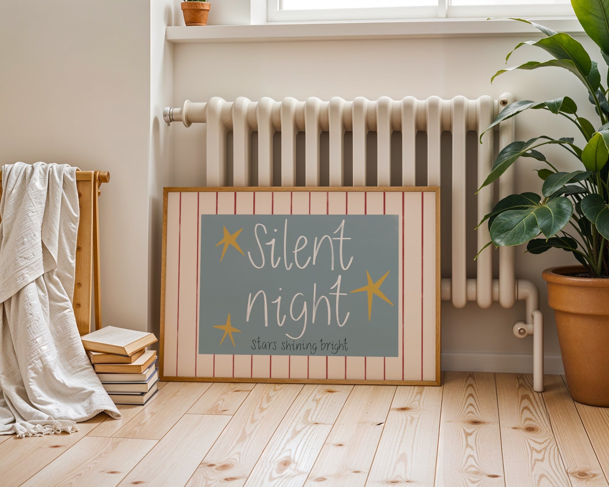 Framed artwork with 'Silent Night' text in a room with a radiator and plant.