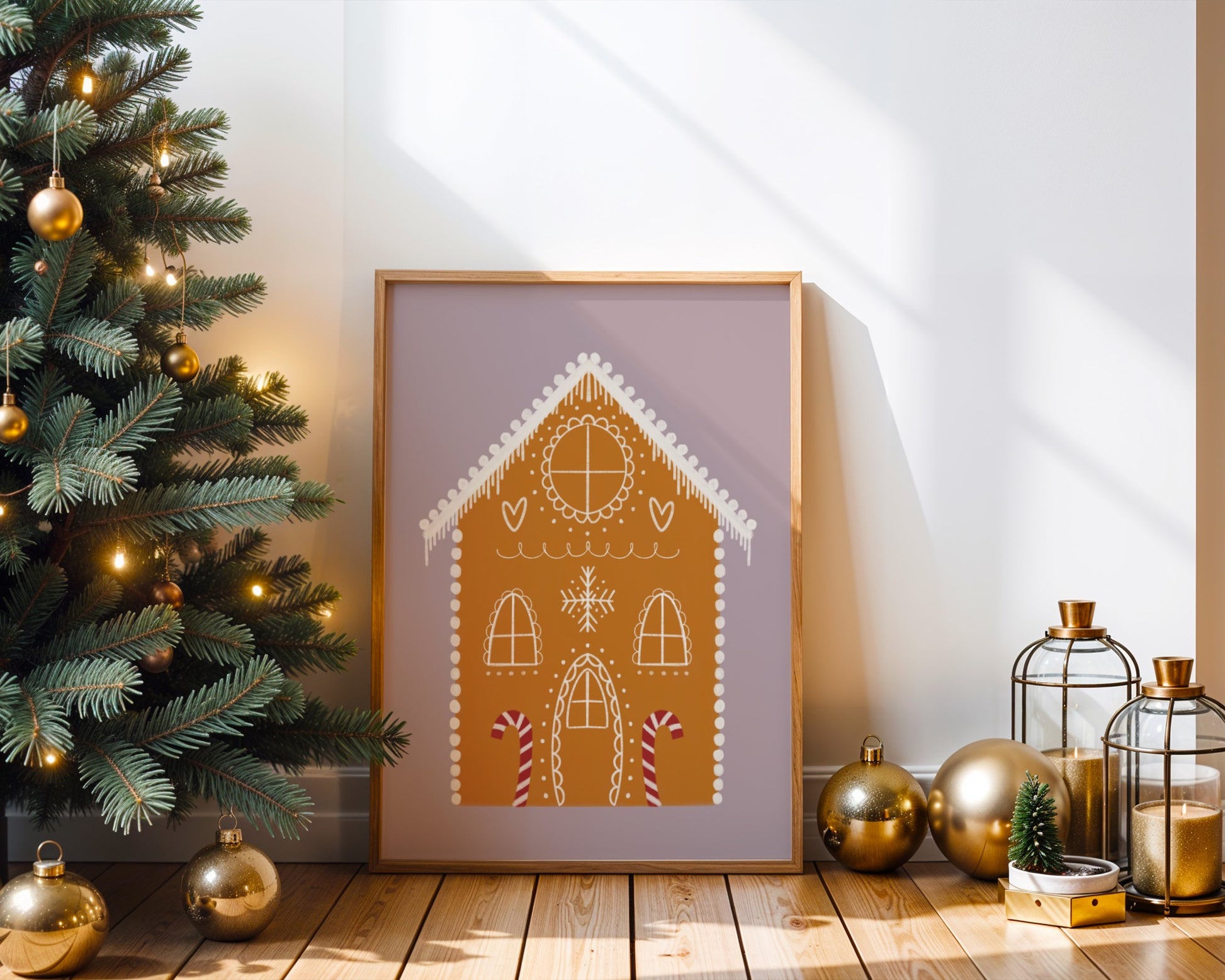Framed gingerbread house art on a wooden floor with Christmas decorations.