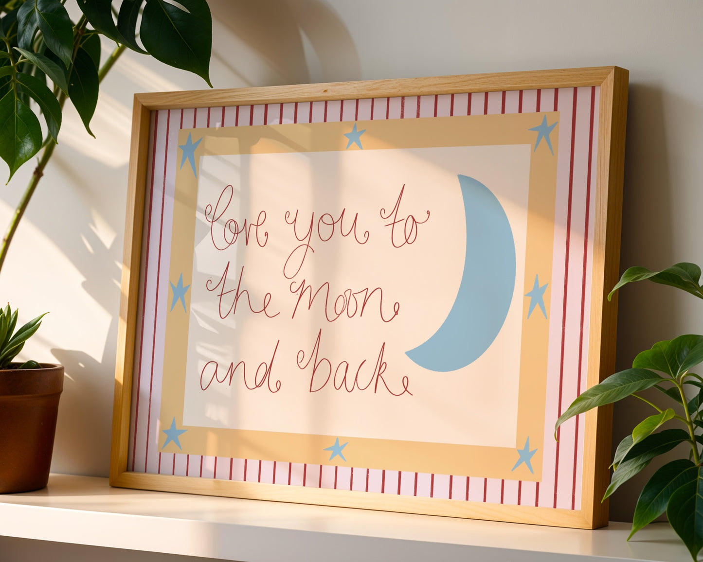Framed artwork with 'Love you to the moon and back' text and a blue crescent moon on a striped background.