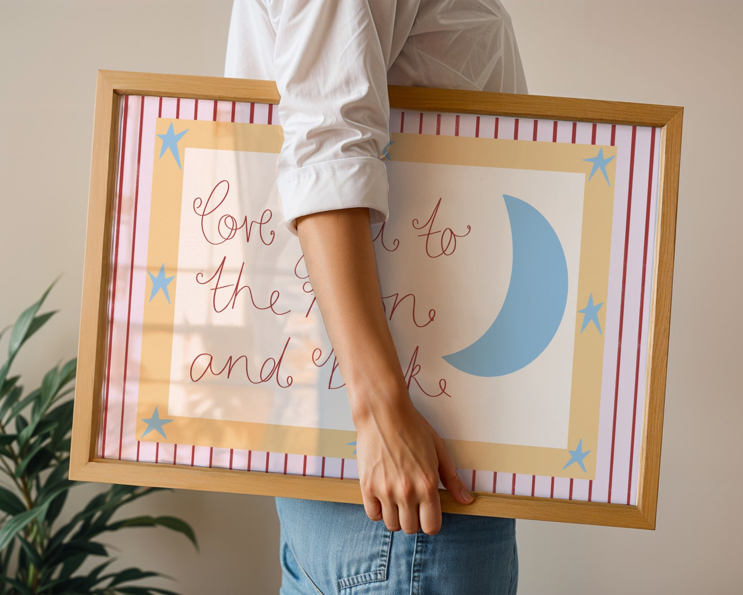 Person holding two framed prints with decorative designs and text.