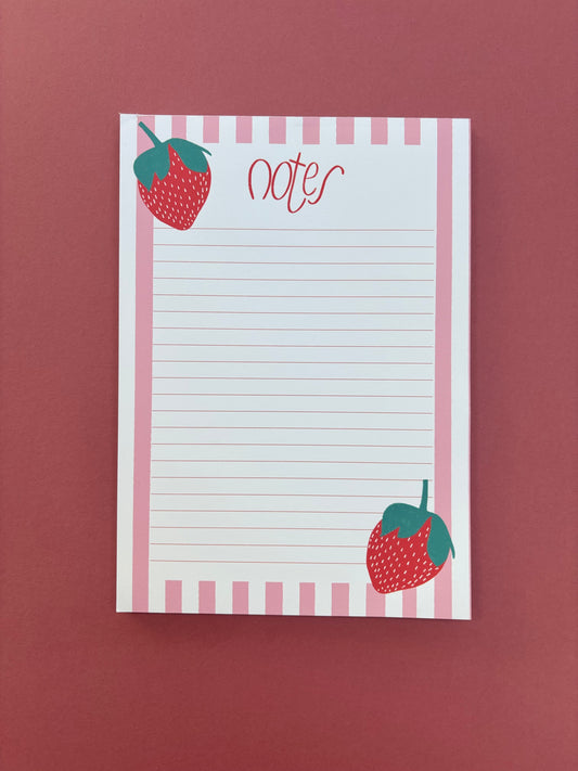 Pink and white striped notepad with a strawberry illustration on each corner. The notepad has the word ‘notes’ written in cursive at the top.