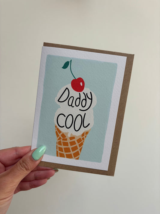 A6 white greeting card with mint green background featuring vanilla ice cream with cherry on top and wording ‘Daddy Cool’ . Features brown Kraft envelope.