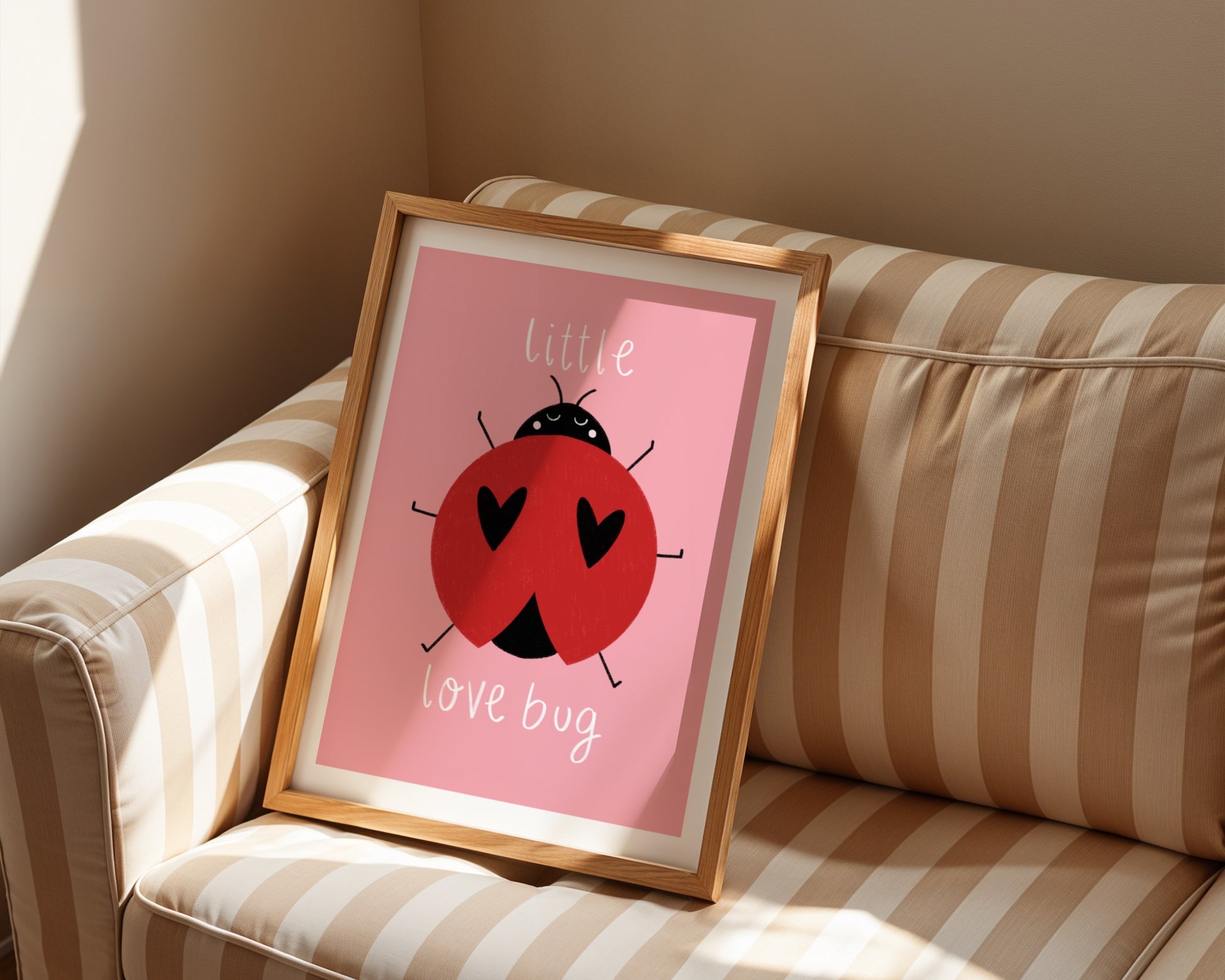 Kids wall art with pink background,  a hand drawn illustration of a ladybird with face and the words “little love bug” In white handwritten text.