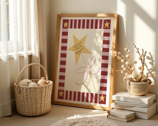 Kids wall art with pink and burgundy striped border and yellow stars in the corners and a central illustration of yellow star wand tied with a pink bow and words “you are magic” 
