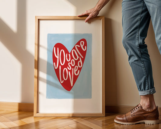 Kids wall art with blue background a red heart illustration featuring “you are so loved” quote