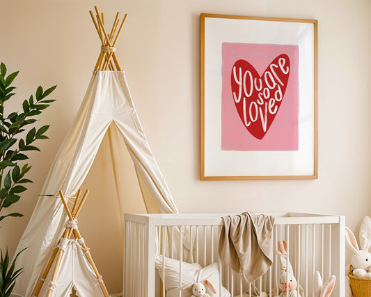 Kids wall art with pink background a red heart illustration featuring “you are so loved” quote